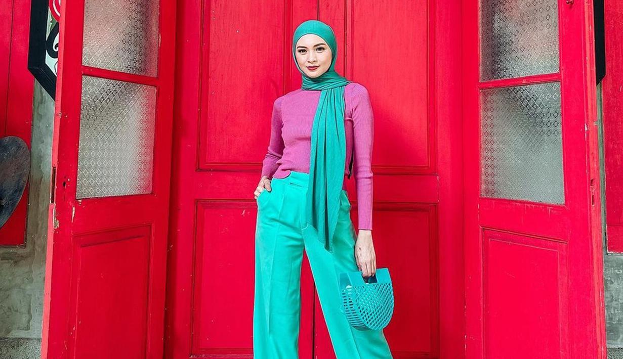 Tampil dengan busana berwarna serba tosca, Donita memilih untuk memadukannya dengan sebuah turtle neck berwarna ungu. Gaya hijab yang sederhana serta tas yang unik ini tak lepas dari perhatian netizen. (Liputan6.com/IG/@donitabhubiy)