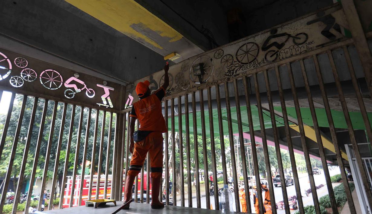 Bersama jajaran Suku Dinas Bina Marga, petugas PPSU melakukan pengecatan ulang, pembuatan mural, pembersihan debu, serta perapian tanaman di jalur hijau sekitar arena. Tampak dalam foto, salah satu petugas Penanganan Prasarana dan Sarana Umum (PPSU) melakukan pengecatan di kolong jembatan layang Pasar Rebo, Jakarta Timur, Jumat (8/5/2026). (Kapanlagi.com/Budy Santoso)