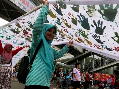 Warga memegang spanduk sepanjang satu kilometer bekas Cap tangan anak-anak Indonesia, di Kawasan Car Free Day, Bundaran HI, Jakarta (24/9). Spanduk tersebut untuk menunjukkan dukungan kepada Etnis minoritas Rohingya di Myanmar. (Liputan6.com/Johan Tallo)