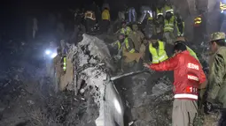 Regu penyelamat mencari korban di antara puing pesawat Pakistan International Airlines yang jatuh di Abbottabad, wilayah Khyber Pakhtunkhawa, Rabu (7/12). Otoritas setempat menyatakan pesawat jatuh di gunung lalu meledak dan terbakar. (AAMIR QURESHI/AFP)