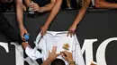 Petenis Bulgaria, Grigor Dimitrov menandatangi jersey yang disodorkan penggemarnya setelah menang atas Pablo Cuevas dari Uruguay pada pertandingan tunggal putra turnamen Australia Terbuka di Melbourne, Rabu (16/1). (Photo by Greg Wood / AFP)