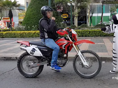 Seorang warga berpakaian seperti zebra berbincang dengan pengendara motor sebagai bagian dari program pendidikan di jalan di La Paz, Bolivia,(5/12). Kegiatan ini cukup menyita perhatian sejumlah pengendara. (REUTERS/David Mercado)