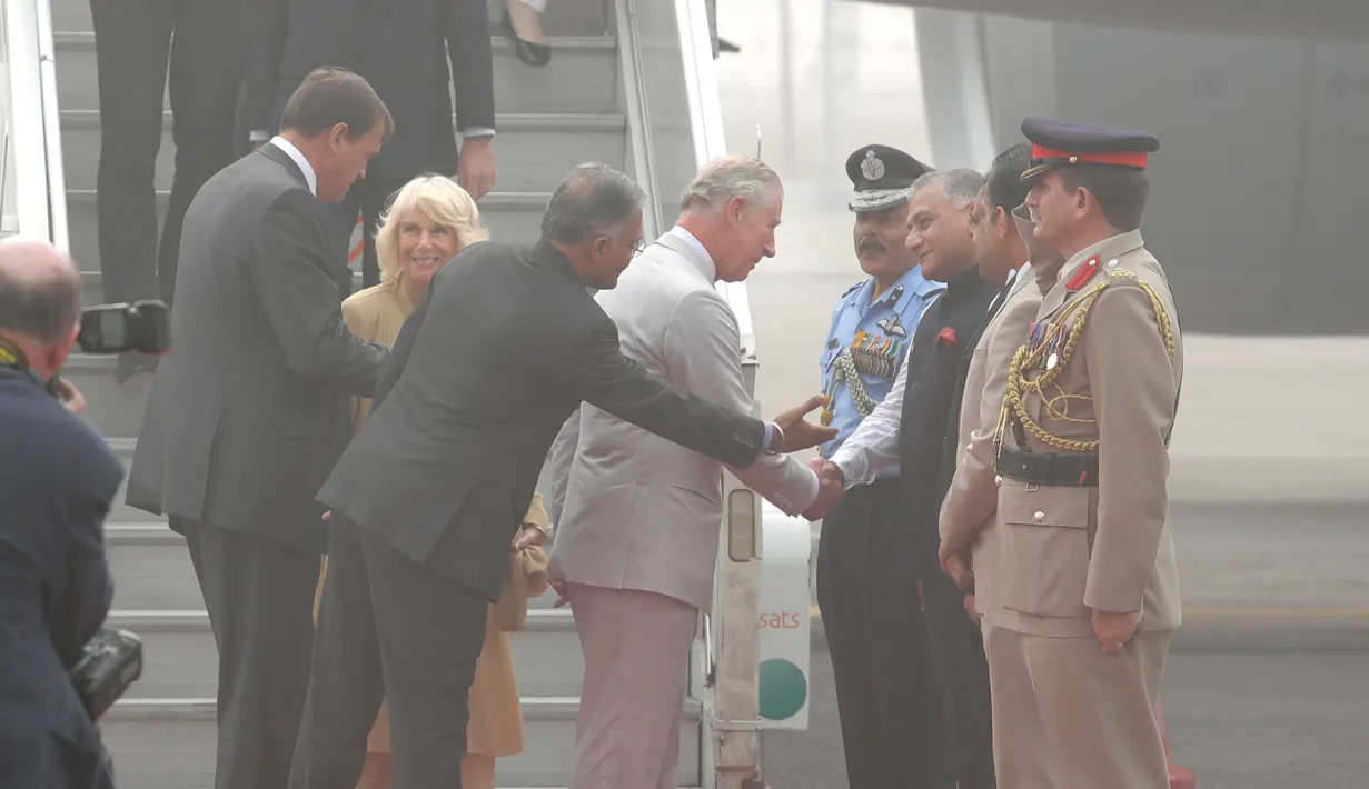 Pangeran Charles berjabat tangan dengan Menlu Muda India V.K. Singh setibanya bersama sang istri, Camilla di New Delhi yang diselimuti kabut asap, Rabu (8/11). Kabut asap tebal akibat polusi udara yang tinggi menyelimuti India. (AP Photo/Manish Swarup)