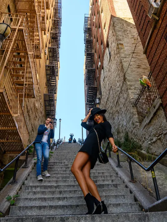 Seorang wanita menari ala Joker di tangga di kawasan Bronx, New York, 23 Oktober 2019. Tangga Joker kini menjadi objek wisata baru di sana, banyak turis berpose sambil menari ala Joker atau sekedar selfie di anak tangganya. (Don Emmert / AFP)