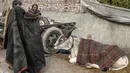 Seorang pemilik bersiap menyelimuti sapinya yang sudah ditutupi selimut di kawasan lama New Delhi, India pada 21 Januari 2020. Hal tersebut dilakukan untuk melindungi sapi agar tetap hangat selama bulan-bulan musim dingin. (Photo by Sajjad HUSSAIN / AFP)