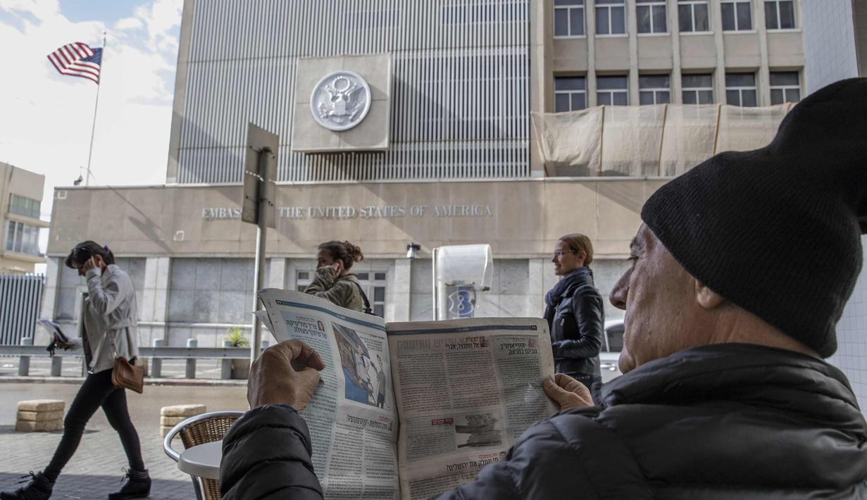 Seorang pria membaca koran saat ia duduk di sebuah kafe di luar kedutaan AS di Tel Aviv (6/12). Presiden AS, Donald Trump resmi mengumumkan Yerusalem sebagai ibu kota Israel. (AFP Photo/Jack Guez)