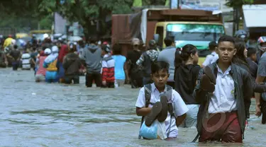 Pelajar berusaha melintasi genangan air ketika banjir merendam Jalan KH Hasyim Ashari, Ciledug, Kota Tangerang, Selasa (10/2/2015). (Liputan6.com/Andrian M Tunay)