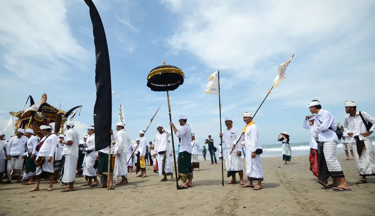 Umat Hindu menyusuri pantai saat menggelar ritual Melasti di Pantai Petitenget, Denpasar, Bali, Senin (4/3). Dalam sejarah, Melasti disimbolkan dengan gunungan sesaji yang dihanyutkan ke laut. (SONNY TUMBELAKA/AFP)