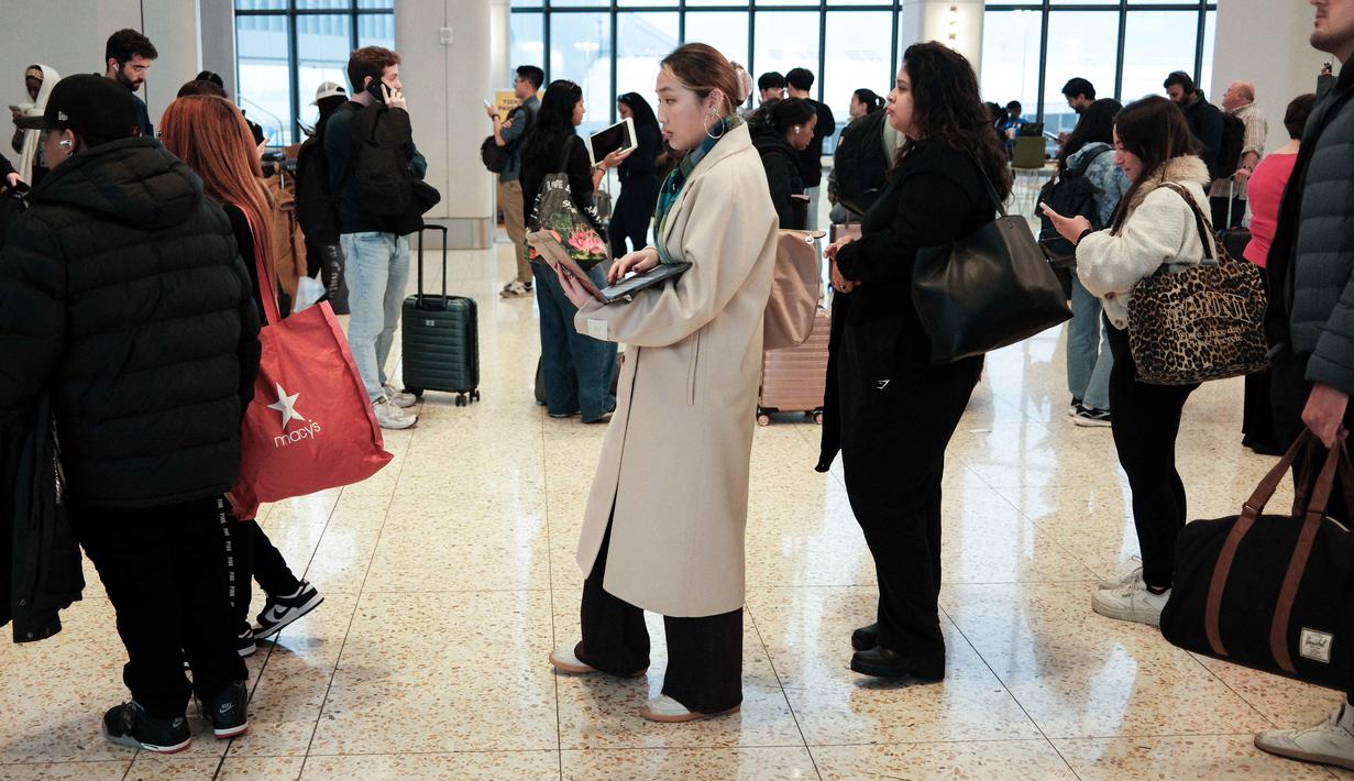 Diketahui, kebijakan ini diambil di tengah penutupan sebagian pemerintahan (government shutdown) yang telah melumpuhkan pendanaan Departemen Keamanan Dalam Negeri (DHS) sejak pertengahan Februari 2026. Tampak dalam foto, antrean para penumpang untuk melewati pemeriksaan keamanan di Bandara LaGuardia, New York pada Minggu 22 Maret 2026. (CHARLY TRIBALLEAU/AFP)