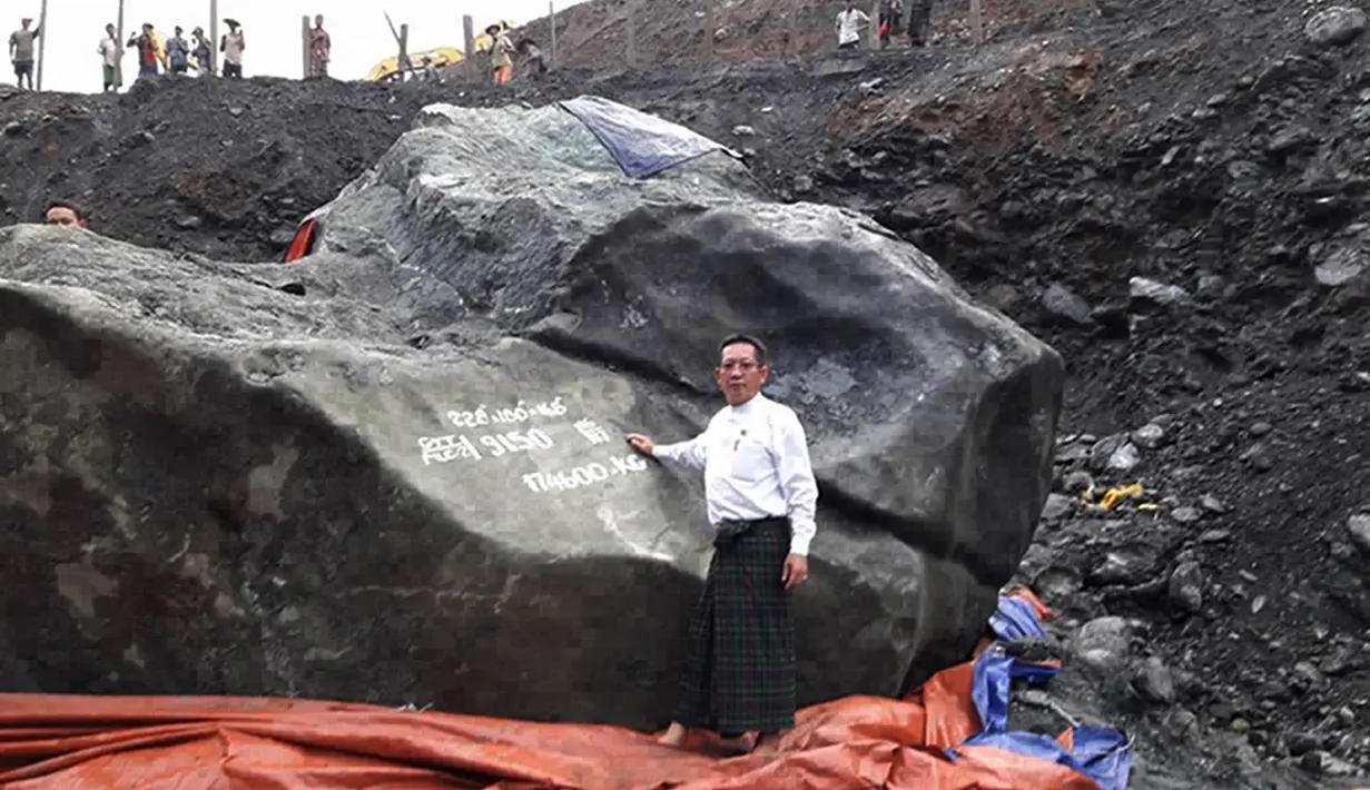 Pejabat setempat, Tint Soe berpose di samping batu giok yang ditemukan penambang di lokasi tambang di negara bagian Kachin, Myanmar, Kamis (20/10). Bongkahan batu giok seberat 174 ton itu dilaporkan tidak bisa dipindahkan dari lokasi penemuan. (STR/AFP)
