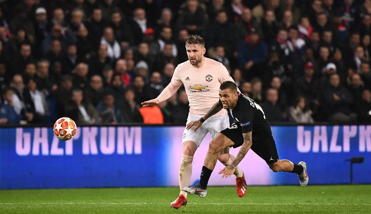 Dani Alves dijatuhkan Luke Shaw pada leg kedua, babak 16 besar Liga Champions yang berlangsung di Stadion Parc des Princes, Paris, Kamis (7/3). Man United menang 3-1 atas PSG. (AFP/Anne-Christine Poujoulat)