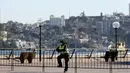 Seorang pejabat keamanan berdiri di depan Harbour Bridge, Sydney, Australia, Selasa (13/7/2021). Lima juta penduduk Sydney akan berada dalam lockdown COVID-19 untuk dua minggu lagi. (Brendon THORNE/AFP)
