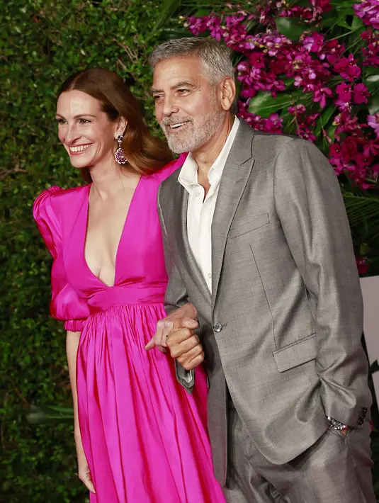 Aktris AS Julia Roberts (kiri) bergandengan tangan dengan aktor AS George Clooney saat tiba untuk pemutaran perdana "Ticket to Paradise" di Regency Village Theatre di Westwood, California, pada 17 Oktober 2022. (AFP/MICHAEL TRAN)