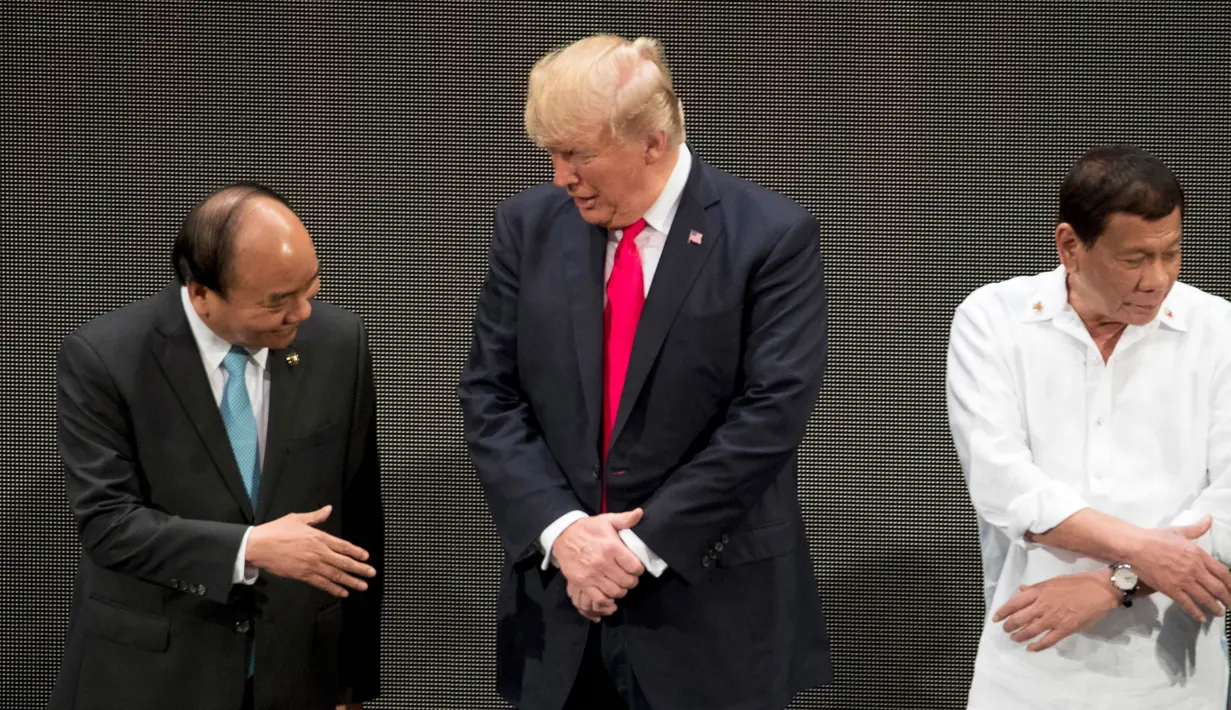 PM Vietnam Nguyen Xian Phuc, Presiden AS Donald Trump dan Presiden Filipina Rodrigo Duterte bersiap melakukan salaman khas ASEAN di upacara pembukaan KTT ASEAN, Manila, Senin (13/11). Trump sulit mengikuti gaya salaman pemimpin lainnya. (AP/Andrew Harnik)