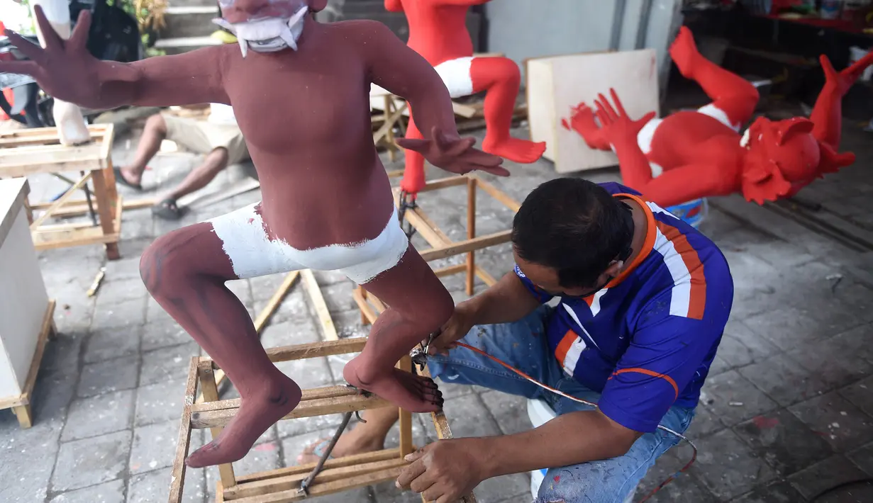 Seorang seniman mencat patung atau yang dikenal ogoh-ogoh sebelum Perayaan Nyepi di Denpasar, Bali (12/3). Ogoh-ogoh sendiri adalah karya seni patung dalam kebudayaan Bali yang menggambarkan kepribadian Bhuta Kala. (AFP Photo/Sonny Tumbelaka)