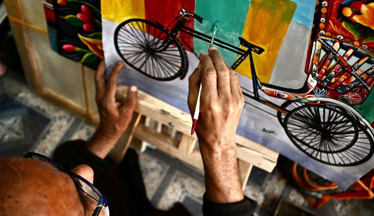 Seniman becak, Hanif Pappu sedang mengerjakan sebuah lukisan di tokonya di Dhaka. (Munir UZ ZAMAN/AFP)