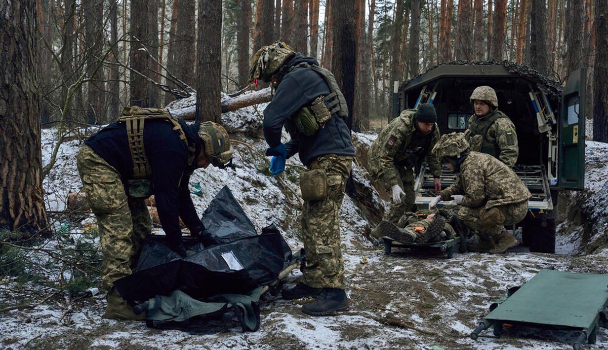 Petugas medis militer memberikan pertolongan pertama kepada tentara yang terluka (kanan) dan memasukkan jenazah tentara yang tewas ke dalam tas dekat Kremenna di wilayah Luhansk, Ukraina, 16 Januari 2023. Hingga saat ini pejabat Ukraina menolak untuk mengonfirmasi jumlah korban dalam perangnya dengan Rusia, setelah ketua Komisi Uni Eropa pada akhir November 2022 lalu memperkirakan bahwa "lebih dari 20.000 warga sipil dan 100.000 tentara Ukraina telah tewas di Ukraina hingga saat ini." (AP Photo/LIBKOS)