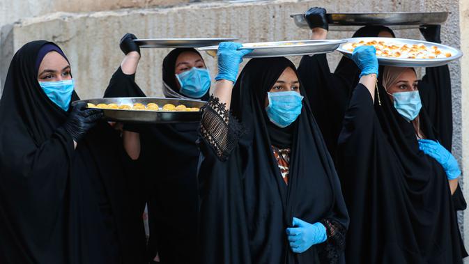 Sejumlah perempuan mengenakan masker untuk melindungi diri dari paparan virus corona COVID-19 saat membawa kue untuk perayaan Idul Fitri yang akan datang di Basra, Irak, Jumat (22/5/2020). Idul Fitri menandai berakhirnya bulan suci Ramadan. (AP Photo/Nabil al-Jurani)