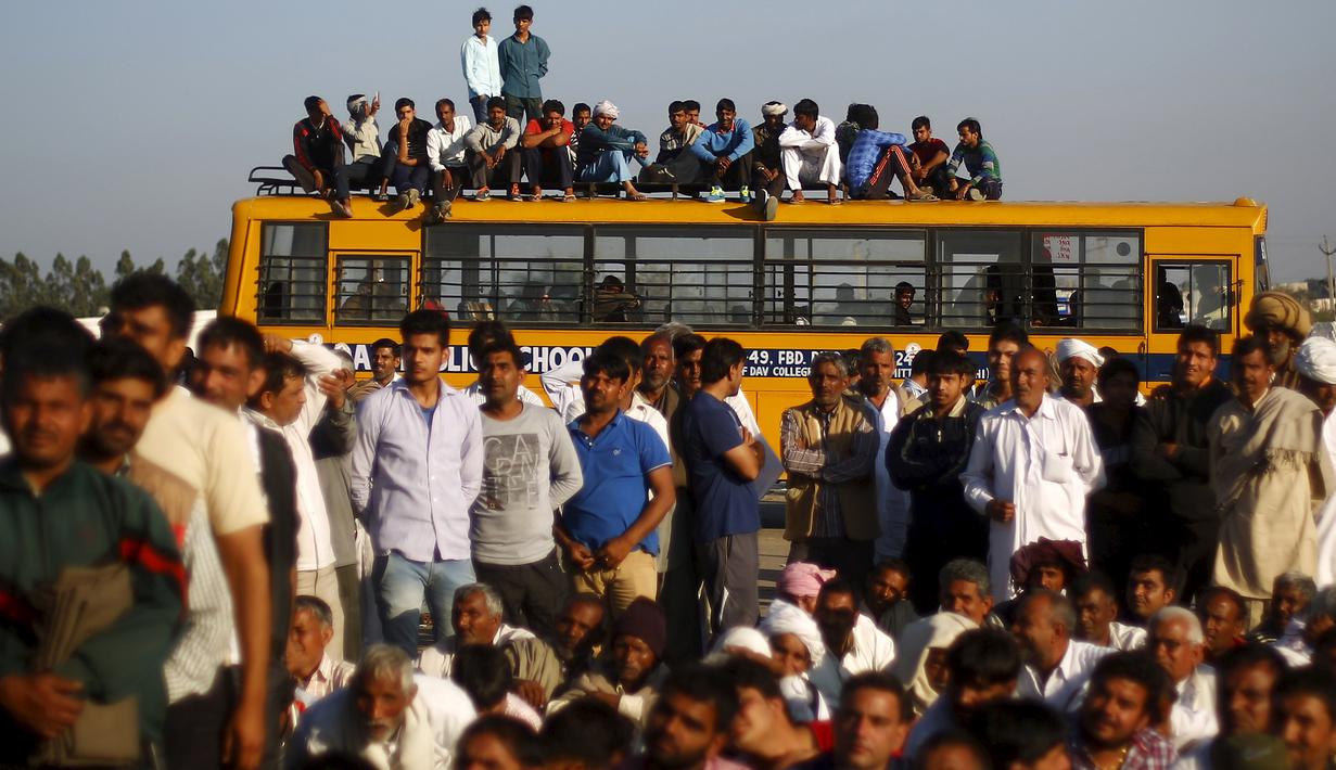 Sejumlah orang duduk di bus sekolah saat memblokir jalan dalam demonstrasi di negara bagian Haryana ke New Delhi, India,Minggu (21/2). Demonstrasi dan aksi kekerasan akibat kelangkaan air di wilayah tersebut menewaskan 10 orang. (REUTERS/Adnan Abidi)