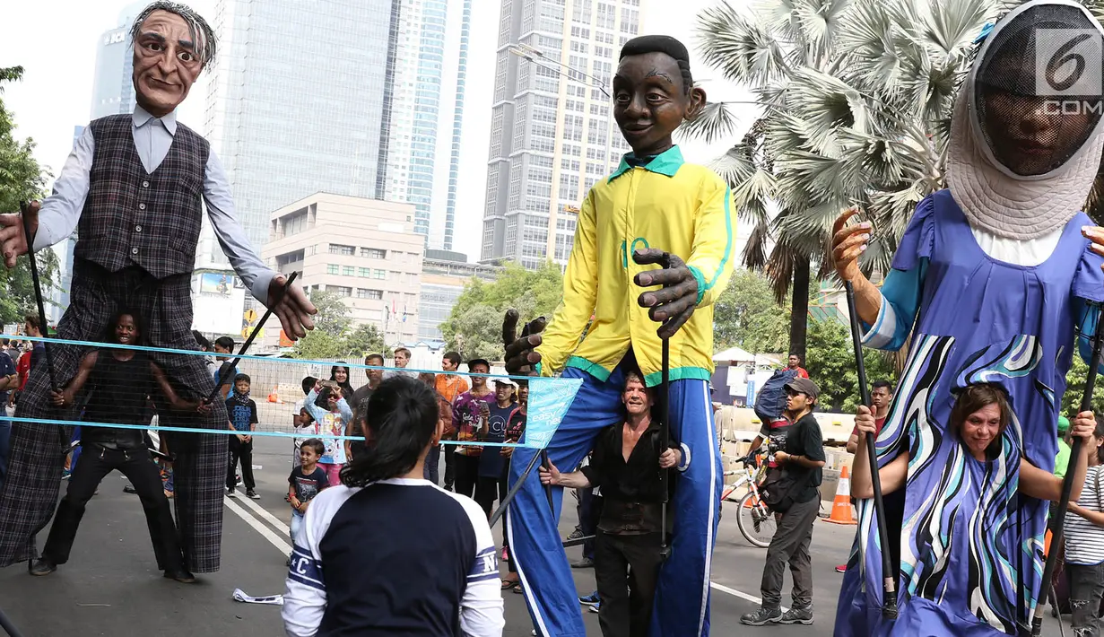 Empat boneka asal Prancis dari Kelompok teater Les Grandes Personnes hibur warga saat bermain bulutangkis di CFD di Jakarta, Minggu (9/7). Kedubes Prancis dan Institute Francais Indonesia menggelar acara penggalangan. (Liputan6.com/Immanuel Antonius)