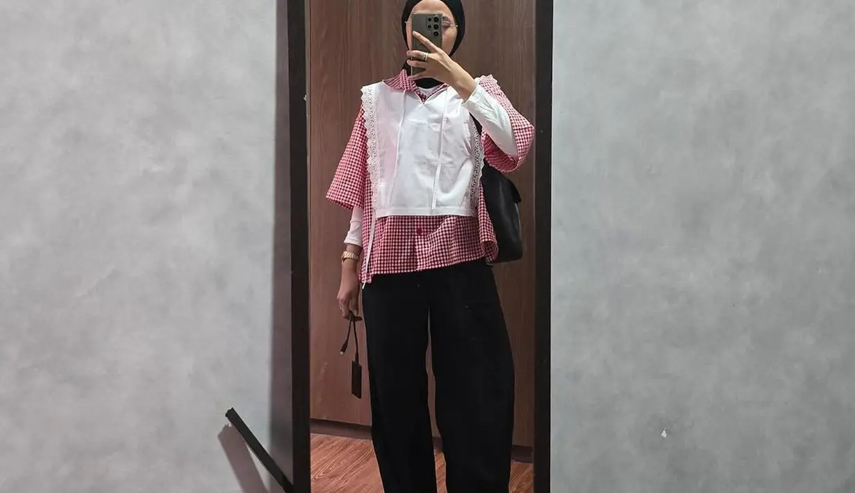 Di potret ini, Feby memadukan kemeja kotak-kotak lengan pendek dengan manset dan collar vest putih. Oversized pants dan hijab hitam jadi sentuhan netral [@fbyputrinc]
