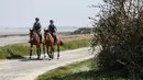Polisi berkuda berpatroli dekat pantai selama lockdown nasional untuk melawan virus corona COVID-19 di Cancale, Prancis, Sabtu (11/4/2020). Prancis masuk periode lockdown pada pertengahan Maret lalu. (AP Photo/David Vincent)