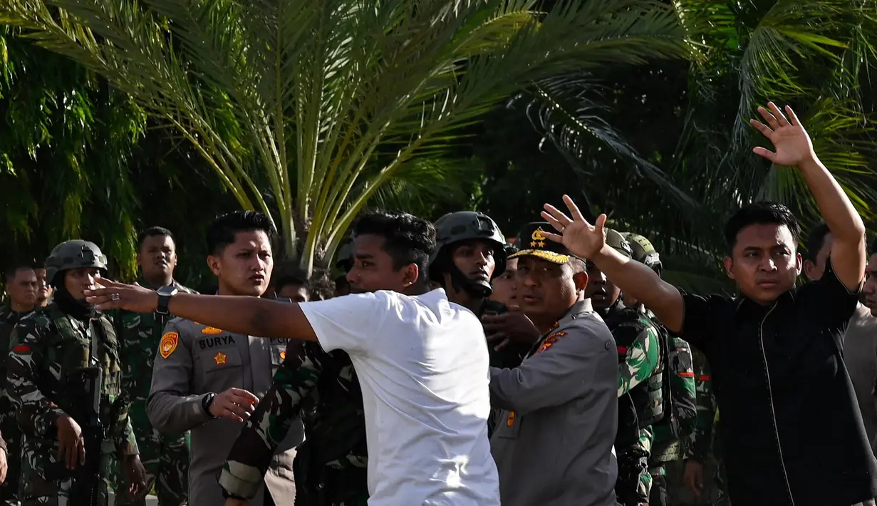 Para tentara berupaya menenangkan pengunjuk rasa yang marah saat mereka menurunkan bendera Gerakan Aceh Merdeka (GAM) yang dikibarkan berdampingan dengan bendera nasional Indonesia dalam sebuah unjuk rasa di Masjid Raya Baiturrahman, Banda Aceh, Sabtu, 15 September 2026. (AFP/ Chaideer Mahyuddin)