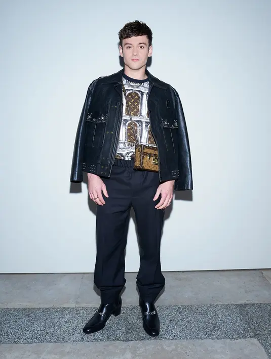 Atlet loncat indah fenomenal, Tom Daley tampil kece dengan balutan busana serba hitam-cokelat. Peraih medali emas Olimpiade Tokyo 2020 ini mengenakan jaket, t-shirt, dan pants warna hitam. Gayanya disempurnakan dengan sling bag warna cokelat. (Dok/Louis Vuitton).