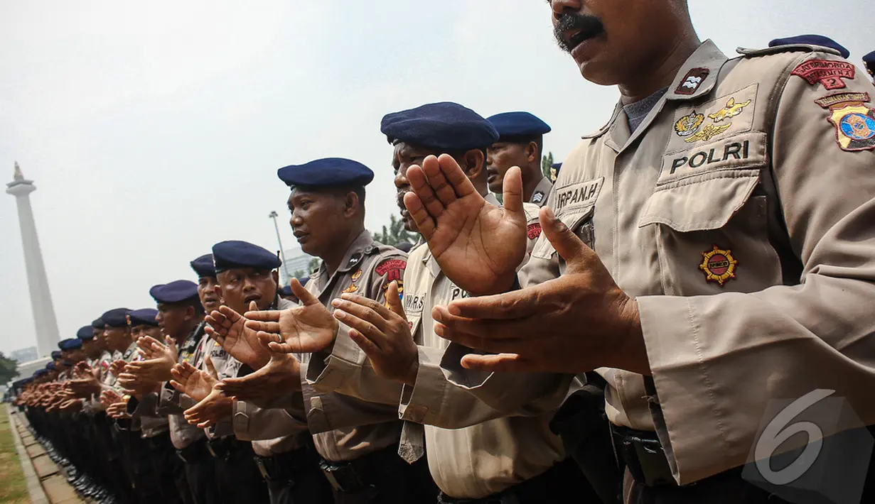 Para Polisi bernyanyi bersama sambil bertepuk tangan untuk memompa semangat saat apel pengamanan pelantikan presiden dan wakil presiden di halaman Monumen Nasional, Jakarta, Jumat (17/10/2014) (Liputan6.com/Faizal Fanani)