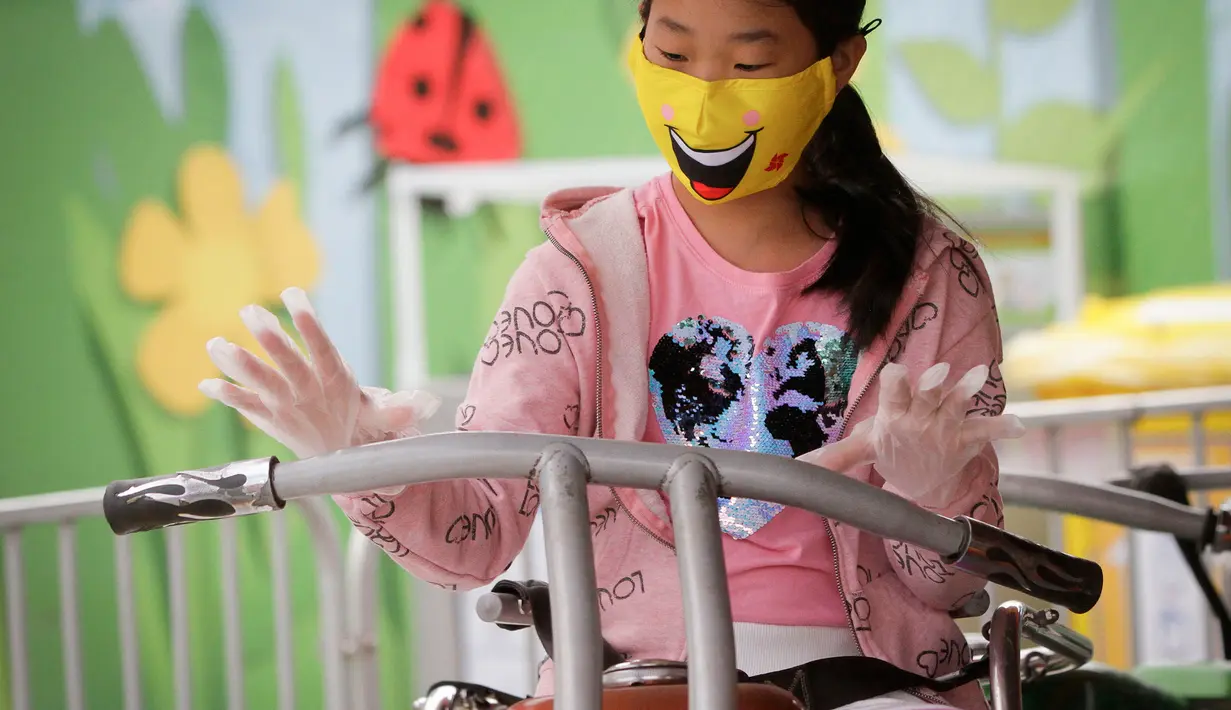 Seorang anak yang mengenakan masker dan sarung tangan menaiki wahana di Playland Amusement Park, di Vancouver, British Columbia, Kanada, pada 10 Juli 2020. Playland Amusement Park dibuka kembali untuk umum pada Jumat (10/7), dengan langkah-langkah protokol kesehatan. (Xihua/Liang Sen)