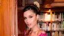 Berpose di tengah nuansa klasik perpustakaan dengan sentuhan kayu ukir yang hangat, Cinta tampil memesona dalam balutan kebaya merah marun dengan aksen brokat transparan di bagian lengan.  [@philipekarunia].