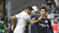 Bek Tottenham Hotspur Cristian Romero berebut bola dengan gelandang Eintracht Frankfurt Daichi Kamada pada laga lanjutan fase Grup D Liga Champions 2022/2023 di Waldstadion, Rabu (5/10/2022) dini hari WIB. Eintracht Frankfurt dan Tottenham Hotspur harus puas berbagi poin usai bermain imbang 0-0. (Daniel ROLAND / AFP)