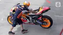 Teknisi Repsol Honda Team mendorong motor tunggangan Marc Marquez saat sesi Warm Up MotoGP di Pertamina Mandalika International Street Sirkuit, Nusa Tenggara Barat, Minggu (20/3/2022). (Liputan6.com/Helmi Fithriansyah)
