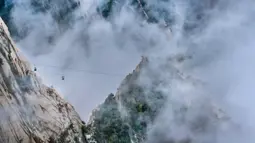 Foto dari udara yang diabadikan pada 20 September 2020 ini menunjukkan kereta gantung yang beroperasi di Gunung Huashan yang diselimuti kabut di Kota Weinan, Provinsi Shaanxi, China barat laut. (Xinhua/Tao Ming)