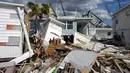 Kathy Hickey (70) dengan hati-hati mengambil jalan melalui puing-puing dari trailer yang hancur di taman rumah mobil tempat dia dan suaminya Bruce pasca terjadinya Badai Ian di Pulau San Carlos, Pantai Fort Myers, Florida, Rabu (5/10/2022). Tim pencari telah menyisir Pantai Fort Myers sepanjang 7 mil selama berhari-hari, mencari siapa pun yang masih membutuhkan bantuan. (AP Photo/Rebecca Blackwell)