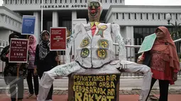 Koalisi Masyarakat Menolak Swastanisasi Air Jakarta (KMMSAJ) saat menggelar aksi membawa patung yang menolak pengelolaan air diberikan kepada pihak swasta di depan Gedung Mahkamah Agung, Jakarta, Jumat (3/6). (Liputan6.com/Faizal Fanani)