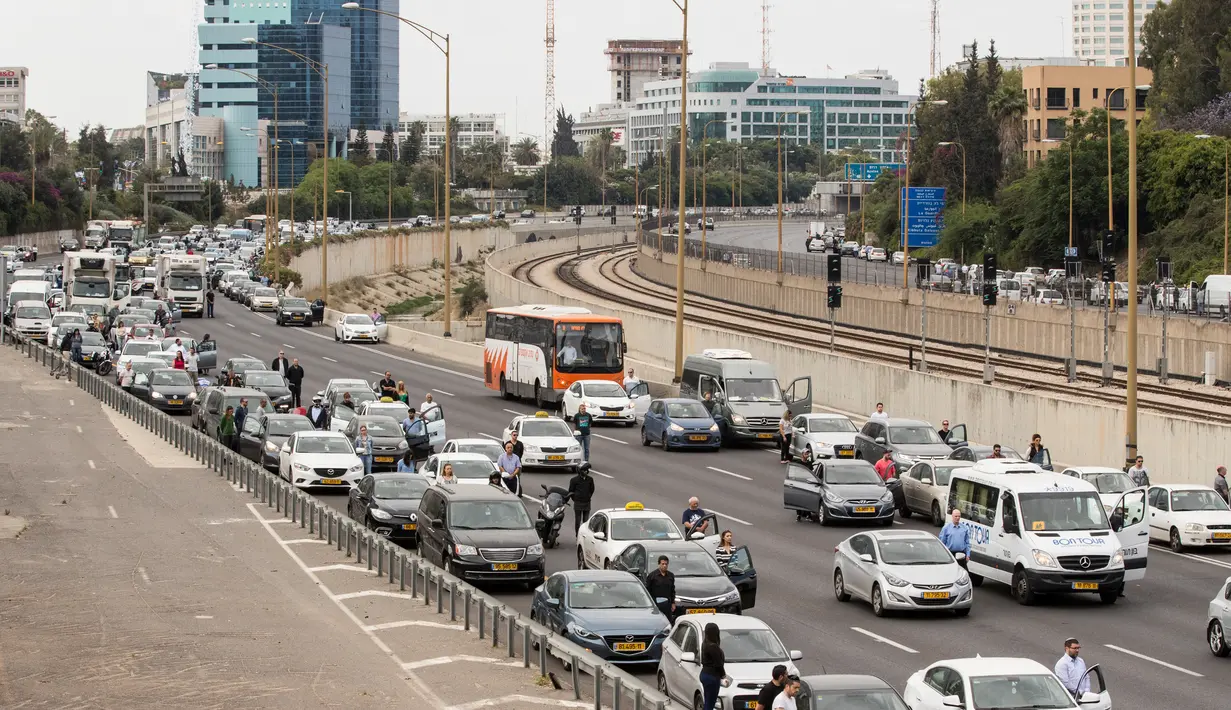 Warga Israel menghentikan laju kendaraan dan keluar dari mobilnya untuk mengheningkan cipta ketika sirine panjang Hari Peringatan Holocaust berbunyi di Tel Aviv, Israel, Senin (24/4). (AFP Foto/Jack Guez)