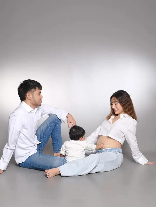 Suami Tasya Revina juga ikut dalam sesi pemotretan dengan nuansa serasi. Duduk berseberangan, ia memperlihatkan tatapan penuh cinta kepada istrinya yang tengah mengandung. Anak pertama mereka pun tampak antusias menyentuh perut sang ibu, seolah menyambut kehadiran calon adiknya. (Liputan6.com/IG/@tasyarevina)