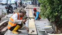 Para pekerja menyelesaikan penataan trotoar di kawasan Matraman, Jakarta, Rabu (9/11). Dinas Bina Marga DKI menyatakan penataan 39 titik trotoar telah mencapai 70 persen dan ditargetkan selesai pertengahan Desember 2016. (Liputan6.com/Immanuel Antonius)