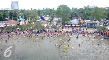 Ribuan pengunjung berenang di Pantai Ancol, Jakarta, Sabtu (26/15). Memasuki libur Tahun Baru sejumlah warga memadati tempat rekreasi di kawasan Ibukota tersebut. (Liputan6.com/Gempur M Surya)