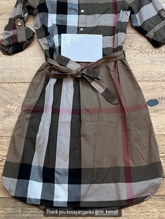 Titi Kamal pun memberi hadiah dress dari Burberry, melihat laman vitkac.com, dress motif tartan coklat tersebut seharga sekitar Rp7,8 jutaan. [@sandradewi88]