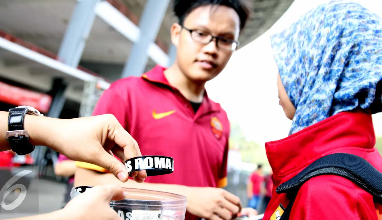 Seorang pedagang menawarkankan gelang bercorak tim Liga Italia, AS ROMA di Stadion Utama Gelora Bung Karno, Jakarta, Sabtu (25/7/2015). Para pedagang mengaku dagangan mereka laris jelang pertandingan AS Roma. (Liputan6.com/Helmi Afandi)