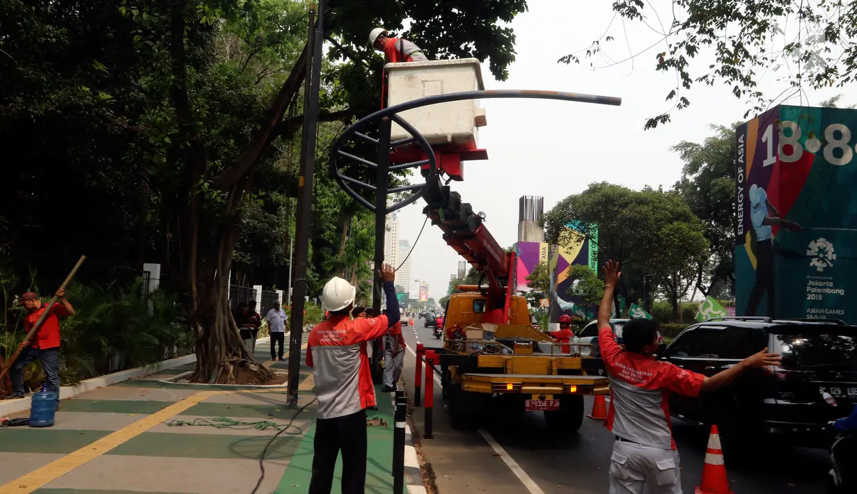 Petugas Suku Dinas PE Jakarta Pusat bersama Satgas PJU, mencabut dan menggeser tiang listrik dan lampu penerangan jalan yang menghalangi jalur sepeda di trotoar Jalan Asia Afrika dan Jalan Gelora, Senayan, Jakarta, Rabu (1/8). (Liputan6.com/Johan Tallo)