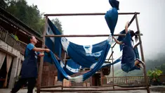 Dua orang perempuan menjemur kain di sebuah bengkel kerja di Desa Etnis Dong Fengdeng di Wilayah Rongjiang, Provinsi Guizhou, China pada 6 September 2020. Warga setempat memanfaatkan kondisi cuaca musim gugur yang mendukung untuk membuat kain tradisional kelompok etnis Dong. (Xinhua/Liu Xu)