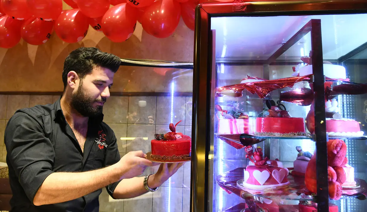 Pembuat kue memegang sebuah kue pada momen Hari Valentine di Damaskus, Suriah, Rabu (12/2/2020). (Xinhua/Ammar Safarjalani)