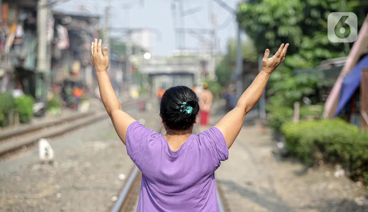 Seorang ibu berjemur di bantaran rel di kawasan pemukiman padat Pejompongan, Jakarta, Selasa (6/7/2021). Berjemur diri di bawah matahari di antara pukul 08.00-11.00 WIB merupakan salah satu upaya yang paling sederhana untuk menjaga kesehatan selama wabah virus COVID-19. (Liputan6.com/Faizal Fanani)