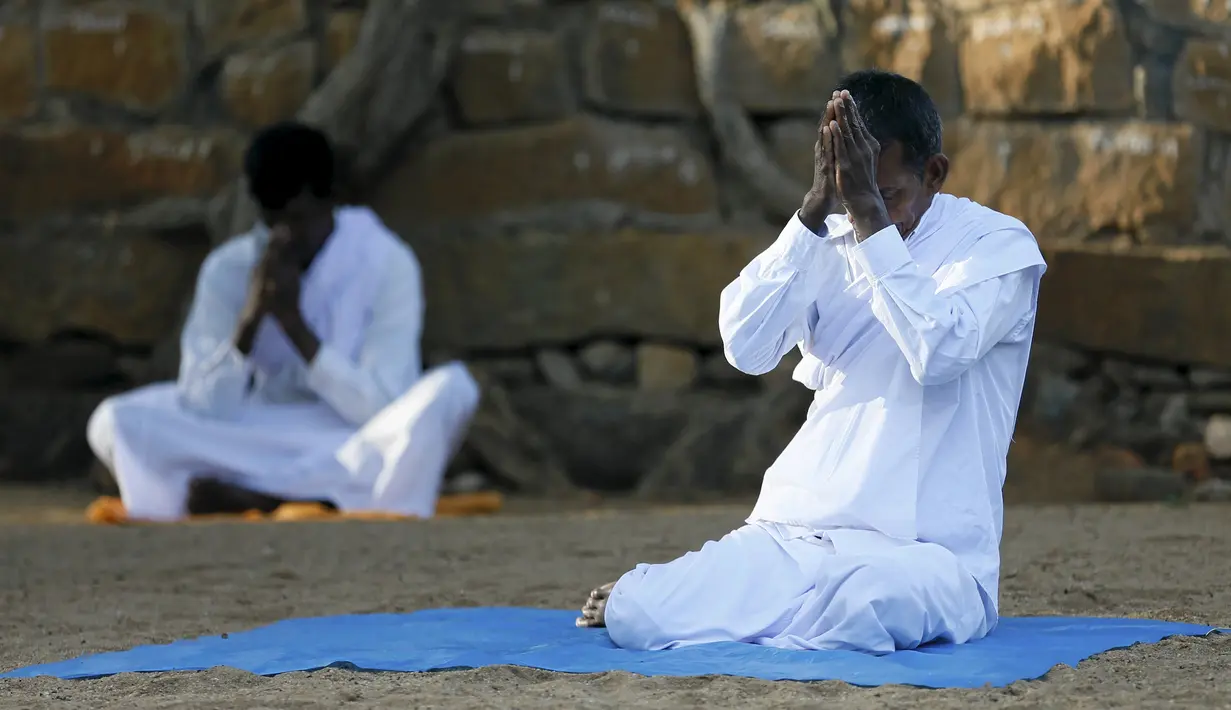 Umat Buddha berdoa di depan Sri Maha Bodhi (the sacred Bo tree of Anuradhapura) pada hari Poya untuk menandai kunjungan kedua Buddha ke Sri Lanka (21/4). Hari Poya dijadikan hari libur Nasional bagi warga Sri Lanka. (REUTERS/Dinuka Liyanawatte)
