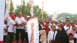 Bupati Mempawah, Erlina (kiri), Direktur Utama Askrindo Andrianto Wahyu Adi (tengah) Direktur Operasional PTPN XIII Ospin Sembiring (kanan) mengibarkan bendera tanda dimulainya jalan sehat  5 KM di Kabupaten Mempawah, Kalimantan Barat, Minggu (18/8/2019). (Liputan6.com/HO/Iqbal)