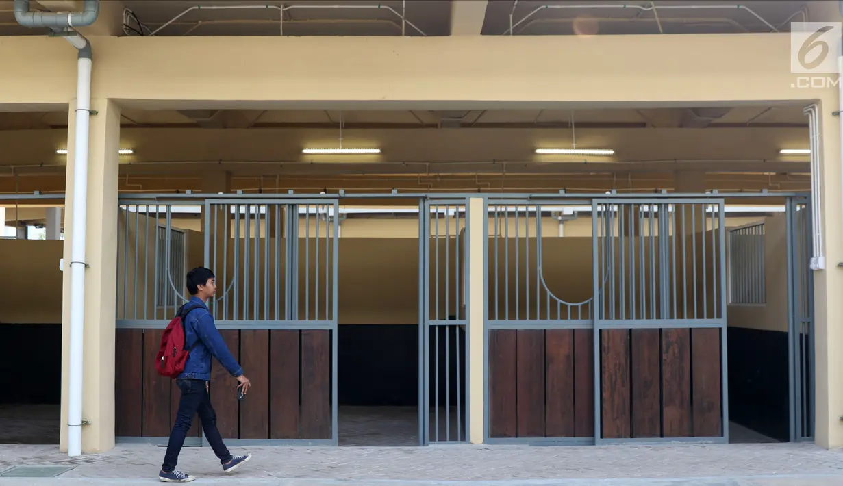 Pewarta melintas di depan istal di kawasan Jakarta International Equestrian Park Pulomas, Jakarta, Kamis (2/8). JIEPP akan menjadi venue tiga cabang equestrian Asian Games 2018. (Liputan6.com/Helmi Fithriansyah)