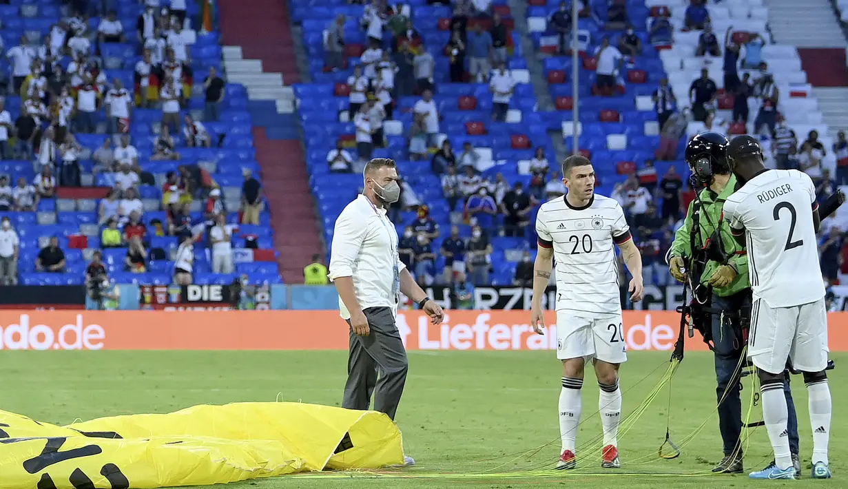 Antonio Rudiger dengan sigap membantu melepaskan alat paragliding yang menempel di badan  aktivis tersebut. (Foto: AP/Pool/Matthias Hangst)